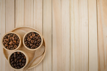 Each species of coffee beans in a wooden cup are placed on a wooden background. copy space.