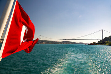 Waving red Turkish flag and a view along turquoise waters of Bosphorus strait on 15 July Martyrs...