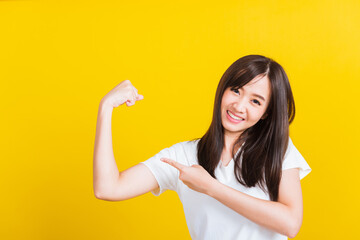 Young woman raises arms biceps confident showing power and strength