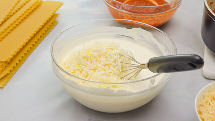 Mix of cream cheese, milk, and mozzarella cheese in a glass bowl close up in woman hands. Step by...