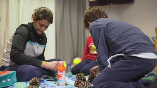 Mother and her two sons, painting and decorating pine cones for Christmas 4K