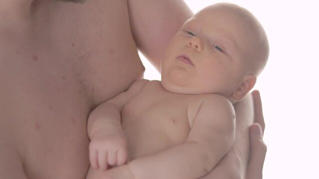 Close-up of a baby in the arms of it’s father. Skin to skin contact.