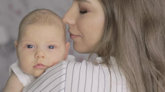 A loving young mother holds her baby and looks at her with love in her eyes.