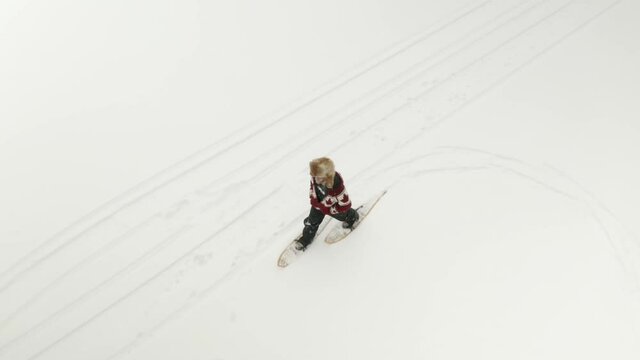 Adult man in large fur hat, walks and plays in traditional snowshoes on frozen lake with his pet dogs in northern Canada.