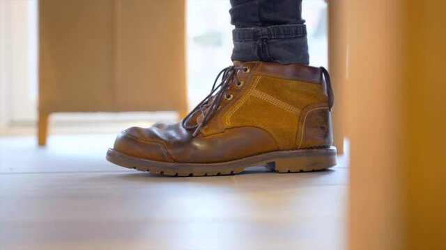 Worn mens brown boots tapping on the floor in anticipation or stressful situation.