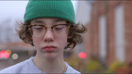 Portrait of teen boy with glasses and green hat outside. - Powered by Adobe