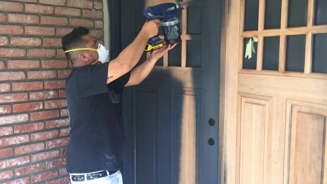 Professional painter applying wood primer to wood doors with spray gun