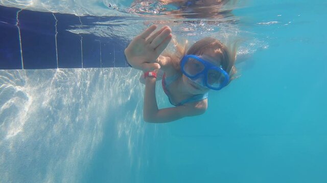 Girl swims underwater in pool and waves. Slow motion