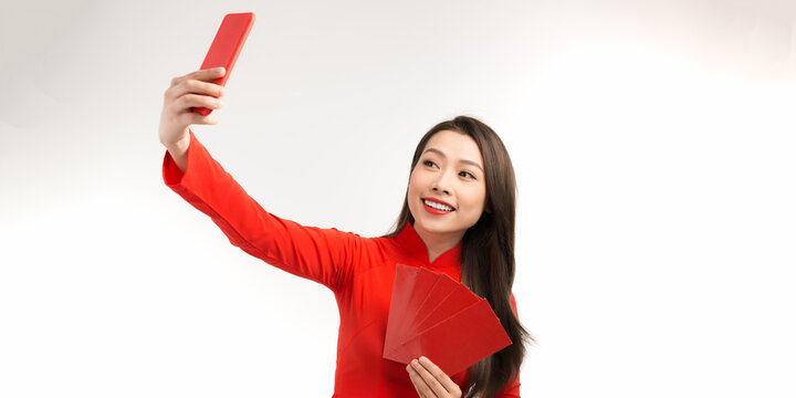 Asian beautiful woman girl in the ao dai red dress up open the red envelope with money, in the lunar New Year.