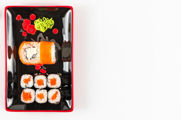 fresh appetizing philadelphia rolls with salmon and soft cheese in black red plates on a white background