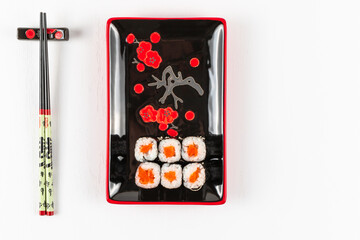 fresh appetizing philadelphia rolls with salmon and soft cheese in black red plates on a white background