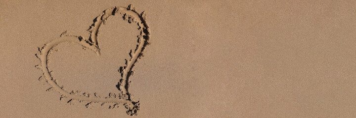 Heart drawn on the sand by sea closeup background. Romantic vacation for newlyweds at sea concept.