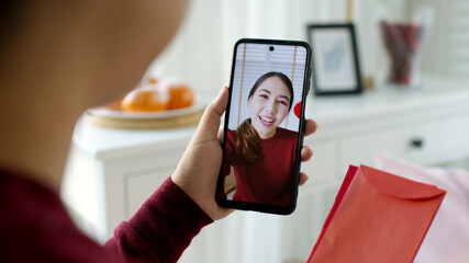 Point of view selfie videocall shot of attractive beautiful young asian lady in red chinese new...