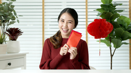 Selfie videocall shot of attractive young asian lady in red chinese new year celebration outfit...