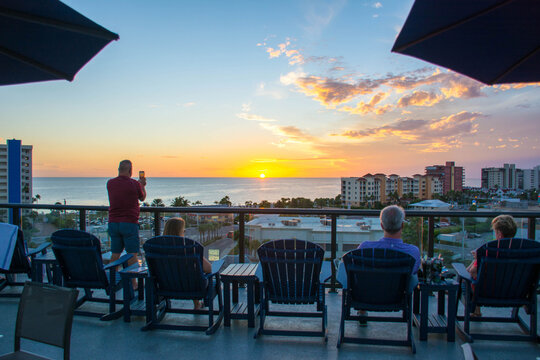 Tourists enjoying a rooftop sunset over the ocean in St Petersburg / Clearwater beach in Florida