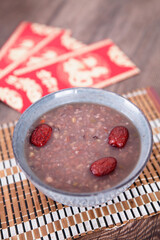 A bowl of Laba porridge and red envelopes in the background