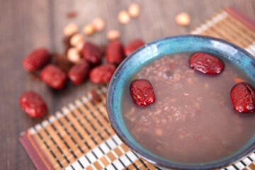A bowl of eight treasures porridge and red dates scattered in the background - obrazy, fototapety, plakaty