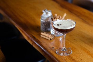 Espresso Cocktail on wooden table with cinnamon and coffee beans in bar or restaurant. Great on it's own, for social media or for a poster.