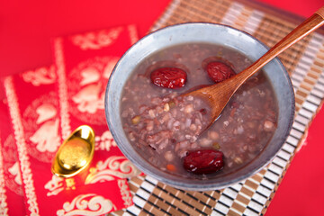 A bowl of Laba porridge and red envelopes on a red background - obrazy, fototapety, plakaty