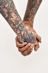 Multicultural relationship. Two tattoed hands of a white woman and dark-skinned man holding each other