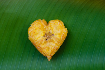 Heart shaped fried plantain isolated on a green leaf © Mabelin