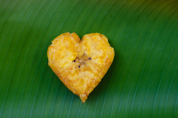 Heart shaped fried plantain isolated on a green leaf