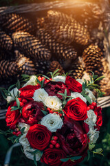 Wedding bouquet of red and white roses in the sunlight outdoor, close-up. Fresh flowers for the bride.