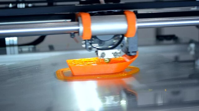 3d printer prints orange object model orange color close-up.