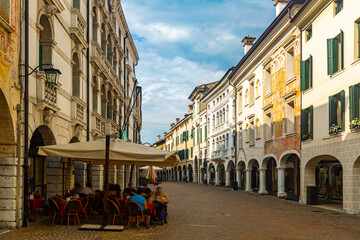 View of typical street with walking people in historical center of Pordenone in sunny autumn day,...