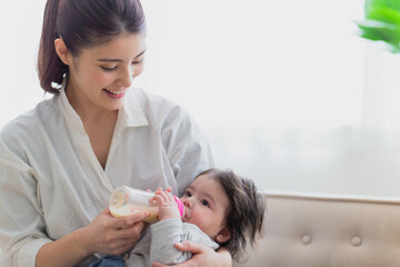 Obraz na płótnie Canvas 赤ちゃんにミルクをあげる女性