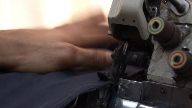Tailor Mending Trousers With Overlock Sewing Machine Footage.