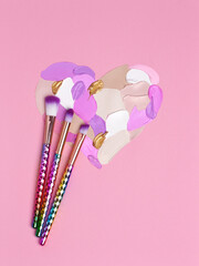 Valentine's Day background. Violet and pink lipstick smeared in the shape of heart. Isolated on pink background. Cosmetic brushes