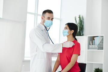 Obraz premium doctor examines woman in medical mask red t-shirt stethoscope 