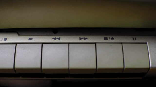 Finger presses the stop button on an old retro tape player, close up