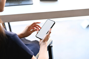 Close up view of  woman freelancer using smart phone check information at her comfortable workplace.