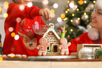 Happy family making tasty gingerbread house in kitchen on Christmas eve