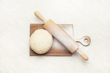 Fresh dough and rolling pin on white background