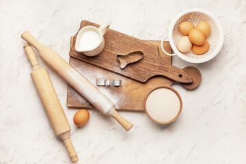 Ingredients for cookies and rolling pins on light background