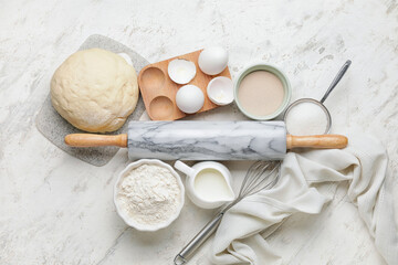 Dough, ingredients and rolling pin on light background