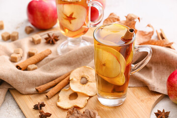 Fototapeta na wymiar Tasty drink with spices and apple slices in cup on light table