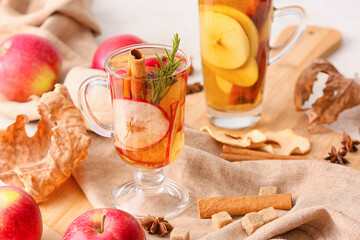 Tasty drink with spices and apple slices in cups on table