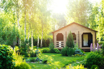 small wooden country house view in summer. Stone pathway, green lawn, conifers and shrubs. Garden...