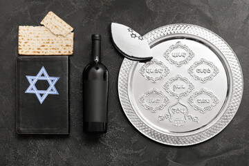 Passover Seder plate with wine, Jewish cap, matzo and Torah on dark background