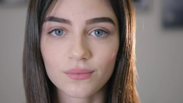 Pleased attractive grey eyed woman demonstrates stylish permanent makeup on brows posing for camera in salon closeup slow motion