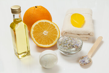 Cut orange with whole one, towel, bottle with aromatherapy oil and sea salt