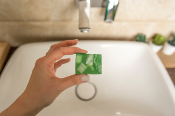 A woman holds a hand made colorful soap in her hand in the bathroom