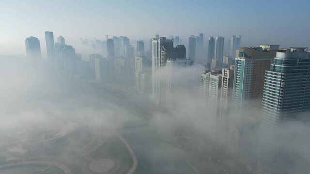 FOG IN UAE: Aerial view of Fog over Sharjah's Khalid Lake, Sharjah skyline covered in the winter morning fog, United Arab Emirates, 4K Drone Footage