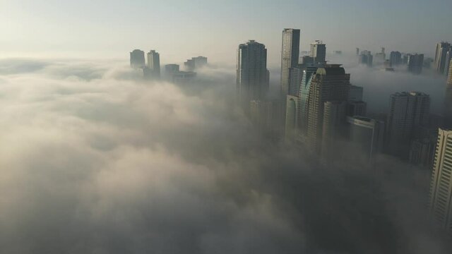 FOG IN UAE: Aerial view of Fog over Sharjah's Khalid Lake, Sharjah skyline covered in the winter morning fog, United Arab Emirates, 4K Drone Footage