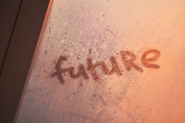 The word future on the window with water drops on sunny background. Fogged window calligraphy. Bright Future concept