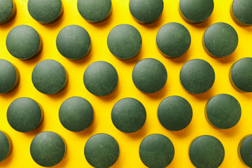Flat lay with spirulina pills on yellow background, top view
